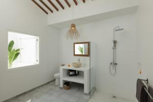 a white bathroom with a toilet and a window at The Bingin Beach Villas' Private Villas in Uluwatu