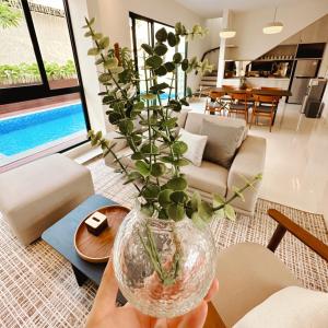 a person holding a vase with a plant in it at Cerita di Villa - Your Second Home in Batu in Tlekung
