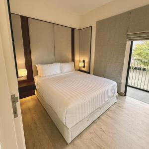 a bedroom with a white bed with a large window at Cerita di Villa - Your Second Home in Batu in Tlekung +10 photos
