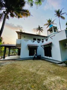 una casa bianca con palme di fronte di Coco Inn Polhena a Matara Altre 6 foto
