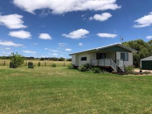 a small white house in a field of grass at The Cottage in Tingoora