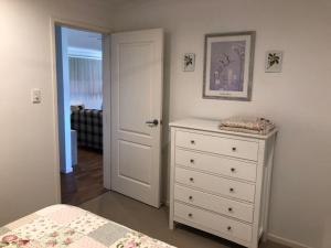 a bedroom with a bed and a dresser and a door at The Cottage in Tingoora