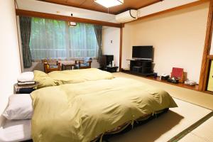九重町佐藤基诺山温泉日式旅馆的卧室里有两张床和一台电视