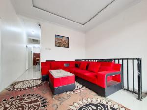 a living room with a red couch and a table at Labella Homestay 1 Syariah Dieng RedPartner in Dieng