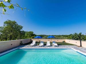 a swimming pool with chairs and umbrellas at Laetitia with pool Comfortable holiday residence in Banjevci