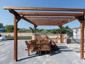 a wooden pergola with a table and chairs on a patio at Laetitia with pool Comfortable holiday residence in Banjevci