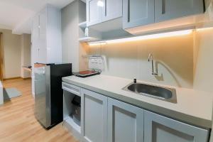 a kitchen with a sink and a black refrigerator at Great Deal and Homey Studio Room Patraland Amarta Apartment By Travelio in Beran-kidul +10 photos