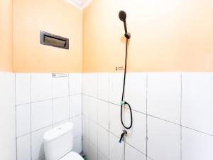 a bathroom with a toilet and a hose on the wall at Labella Homestay 1 Syariah Dieng RedPartner in Dieng