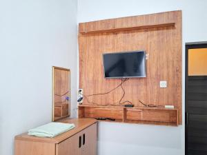 a room with a tv on a wooden wall at Labella Homestay 1 Syariah Dieng RedPartner in Dieng +40 photos