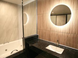 a bathroom with a sink and a mirror and a tub at Mokpo Caltonhill Hotel in Mokpo