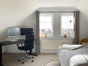 a bedroom with a desk with a computer and a bed at Ferienhaus Inselkieker in Neßmersiel