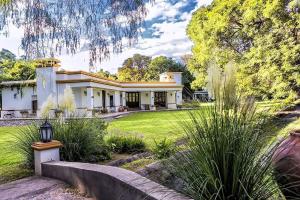 Casa blanca grande con jardín y árboles en Posada del Olivo, en Nonogasta
