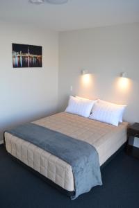 a bedroom with a large bed with a blue blanket at 319 Addington Motel in Christchurch