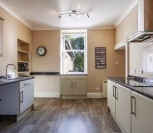 a kitchen with white cabinets and a clock on the wall at Charming Snug Loft Room, Room 4, Beautiful Connel near Oban in Connel