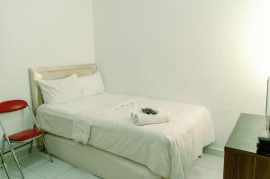 a bedroom with a white bed with a red chair at Comfort Studio Apartment Aeropolis Residence By Travelio in Tangerang +5 photos