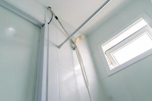 a shower in a bathroom with a window at Comfort Studio Apartment Aeropolis Residence By Travelio in Tangerang