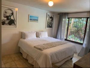 a bedroom with a large white bed with a window at Guest House Mila in Durban +6 photos