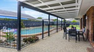 a patio with a fence and a swimming pool at The Poolside Escape in Banksia Beach