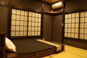 1 dormitorio con 2 ventanas y 1 cama. en Onjuku, en Iwada