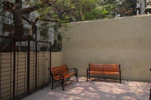 two benches sitting next to a wall with a tree at Golden Residency in Mumbai