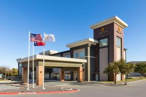 un edificio de oficinas con dos banderas delante en La Quinta by Wyndham Austin NW/Lakeline Mall, en Cedar Park