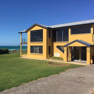 a yellow house with the ocean in the background at Horizons Beachfront Apartment in Port Fairy