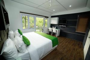 a bedroom with a large white bed with green pillows at Moselberg Riverside Cottages in Munnar