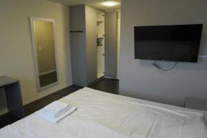 ein Schlafzimmer mit einem weißen Bett und einem Flachbildfernseher in der Unterkunft Hotel Winkel in Schönenwerd