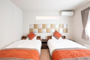 two beds in a small bedroom with a window at Tokuno Zoo Street in Asahikawa