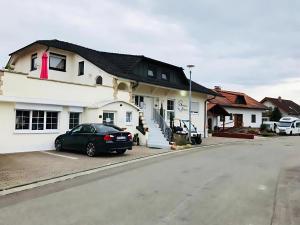 una macchina nera parcheggiata di fronte a una casa bianca di Gästehaus Elzblick a Rust