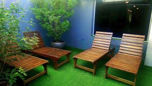 three wooden chairs sitting on a porch with plants at Wassup Youth Hostel in George Town