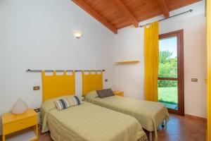 two beds in a room with a window at Villa Baticle in Santa Teresa Gallura