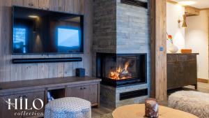 a living room with a fireplace and a tv at Hilo Suite Val d Isere Gelinotte avec Jacuzzi in Val dʼIsère
