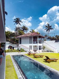 a villa with a swimming pool in front of a house at Marshmallow Bay Boutique Hotel & Surf Point Adults Only in Ahangama