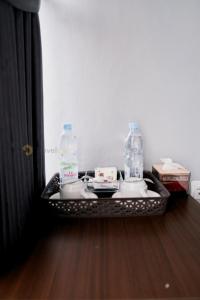 two bottles of water on a tray on a wooden floor at Stigma Kubus By Travelink in Kejajar +10 photos