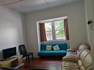 a living room with a blue couch and a window at 5 Bedroom House A with 13 Beds including 6 Double Beds, 2 Single Beds, and 5 Sofa Beds in Auckland