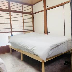 Un dormitorio con una cama con sábanas blancas y ventanas. en Japan House 湯島, en Tokio 8 fotos más