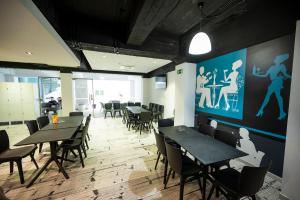 a dining room with tables and chairs and a large screen at Day's Inn Hotel and Residence in Sliema