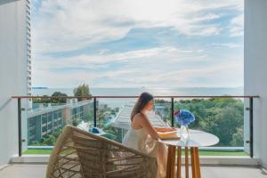 a woman standing on a balcony looking out at the ocean at Renaissance Pattaya Resort & Spa in Na Jomtien