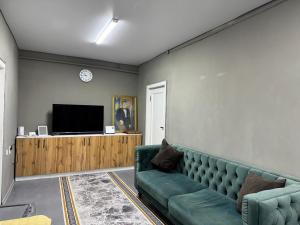 a living room with a green couch and a television at DelLuna in Almaty