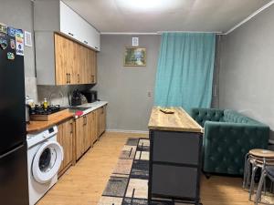 a kitchen with a washing machine and a green couch at DelLuna in Almaty