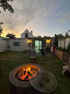 Un patio trasero con una fogata en el césped. en Faraway Cottage 3 Gables Self catering Swellendam, en Swellendam