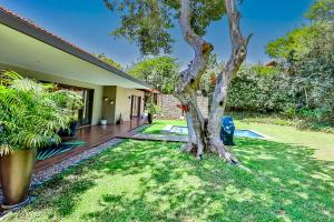a house with a tree in the yard at CasaDulce Zimbali- Exquisite 4 bedroom home with expansive yard and pool in Ballito