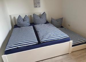a bed with blue and white striped pillows on it at Lenis Strandhaus in Loissin