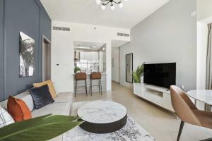 a living room with a couch and a tv and a table at Silkhaus Al Reem island Modern 1BDR in Abu Dhabi
