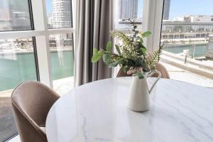 a white table with a vase of flowers on it at Silkhaus Al Reem island Modern 1BDR in Abu Dhabi
