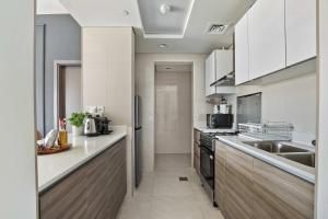 a large kitchen with white cabinets and a sink at Silkhaus Al Reem island Modern 1BDR in Abu Dhabi +7 photos