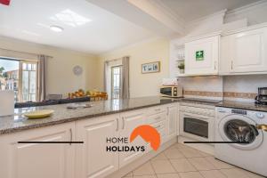 kuchnia z białymi szafkami i pralką i suszarką w obiekcie #269 Pedra Bicos R by Home Holidays w Albufeirze
