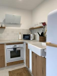 a white kitchen with a sink and a microwave at Appartement vue mer tout confort in Villeneuve-Loubet