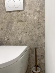 a bathroom with a white toilet and a stone wall at Appartement vue mer tout confort in Villeneuve-Loubet